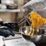 Profesionálna gastronomická fritéza pri príprave hranoliek v reštauračnej kuchyni.